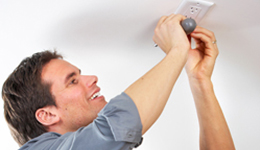 Man replacing the cover of an electrical outlet on the ceiling